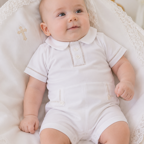 Baby in a white outfit sitting on a white textured surface