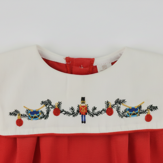 Embroidered design on a red and white fabric with Christmas-themed elements.