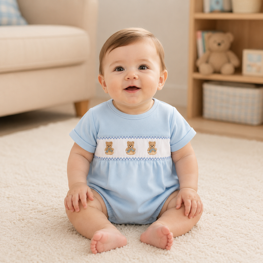 Baby sitting on a carpeted floor wearing a light blue romper with teddy bear designs.