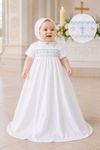 Baby in a white baptism gown with blue embroidery in a church setting