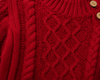 Close-up of a red knitted sweater with cable pattern and buttons.