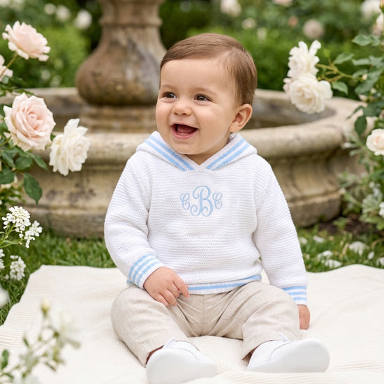 Carriage Boutique personalized white cotton hooded sweater with blue striped trim worn by a smiling baby boy