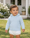Carriage Boutique baby blue cable knit hooded sweater worn by a smiling toddler in a garden setting