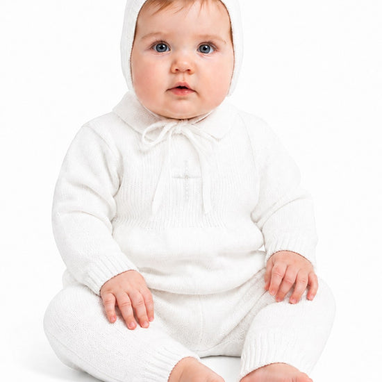 Carriage Boutique baby boy white knit baptism outfit with pearl cross detail and matching bonnet on a seated baby.