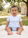 Carriage Boutique baby boy wearing a light blue cotton bubble romper with a white collar sitting on a park blanket