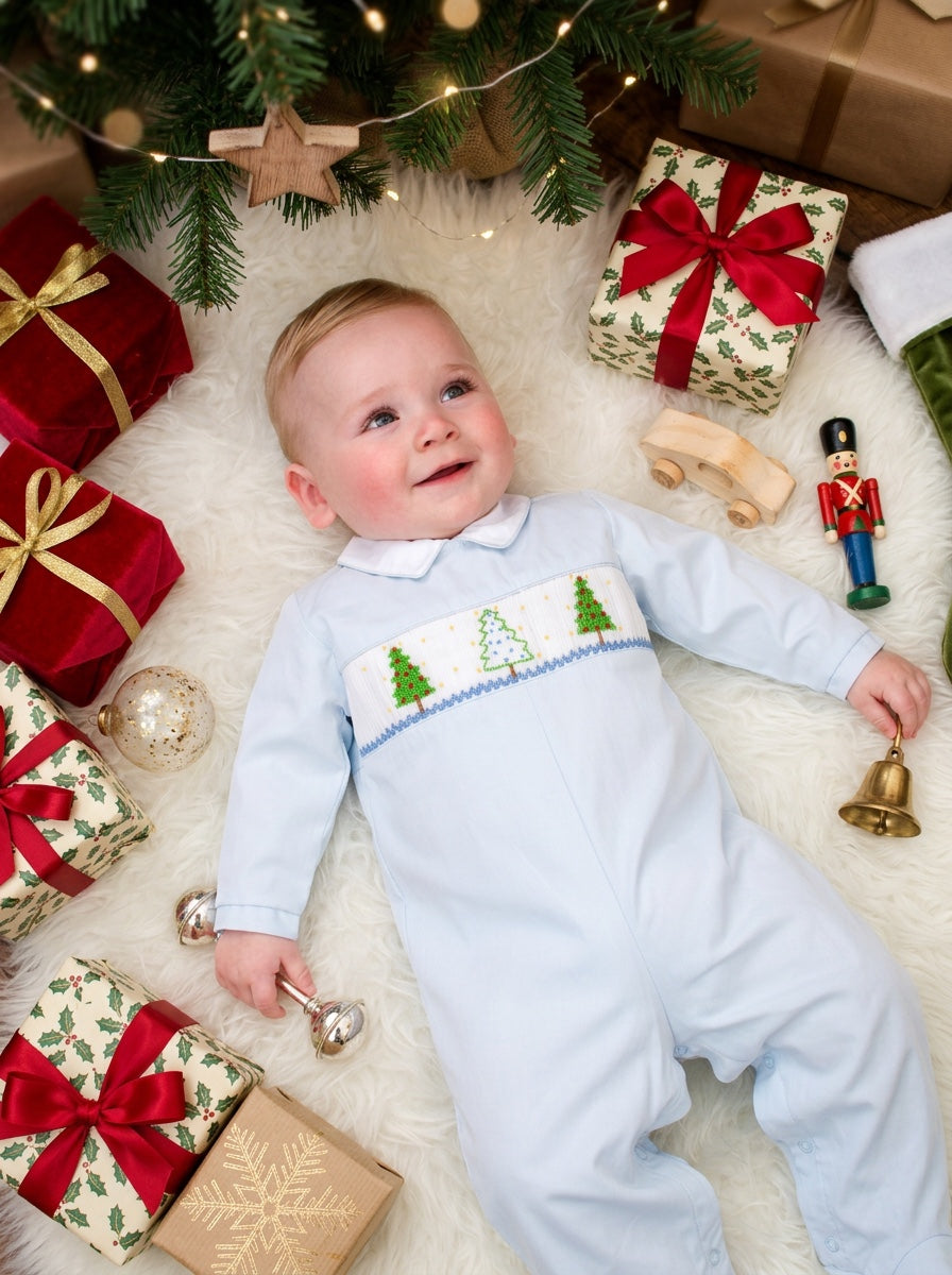 Carriage Boutique baby boy light blue longall with smocked Christmas tree embroidery on a festive holiday background
