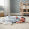 Newborn baby boy wearing a Carriage Boutique light blue hand-smocked day gown and matching bonnet while sleeping.