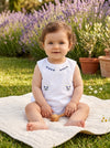 Carriage Boutique baby girl sleeveless cotton diaper set in white with lilac flower bullion embroidery in a garden.