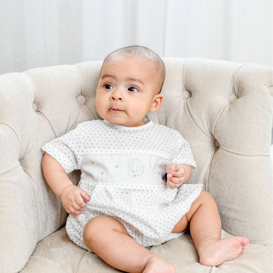 Carriage Boutique white cotton blend baby romper with grey polka dots and hot air balloon smocking.