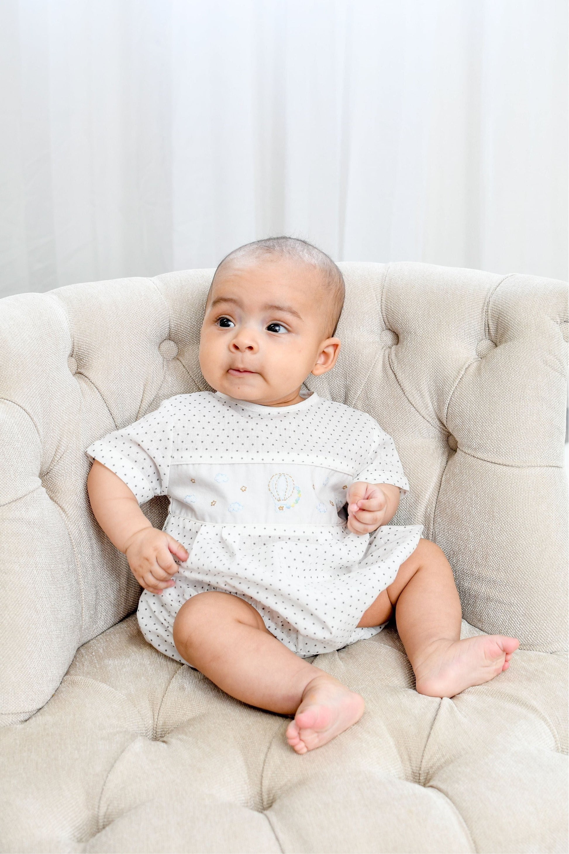 Carriage Boutique white cotton blend baby romper with grey polka dots and hot air balloon smocking.