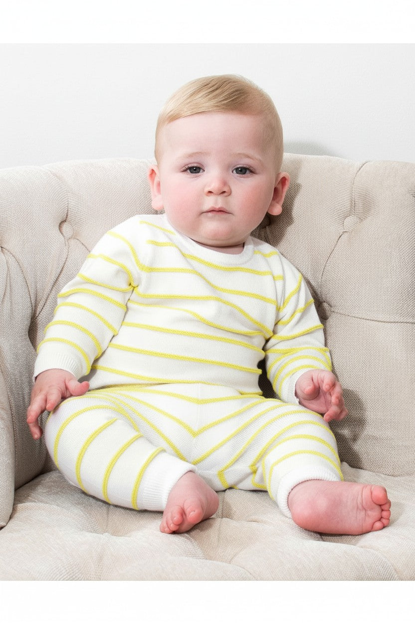 Baby wearing a Carriage Boutique white and yellow striped long-sleeve cotton knit legging set while sitting in a chair