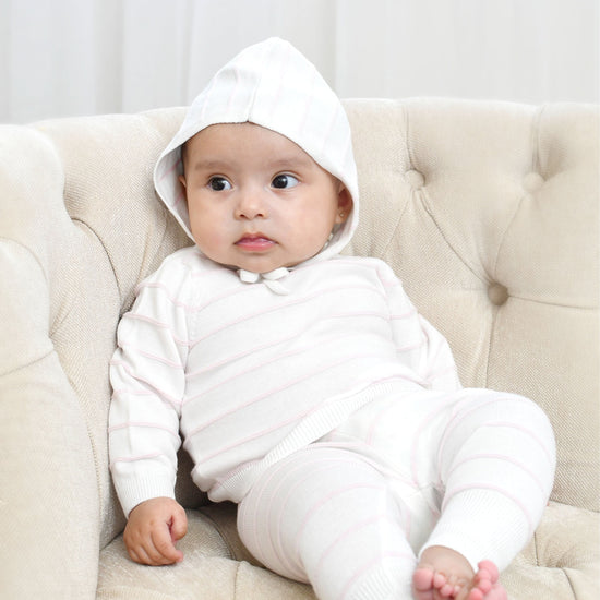 Carriage Boutique baby wearing a creamy white knit set with blush pink stripes, long sleeves, leggings, and a matching hat.