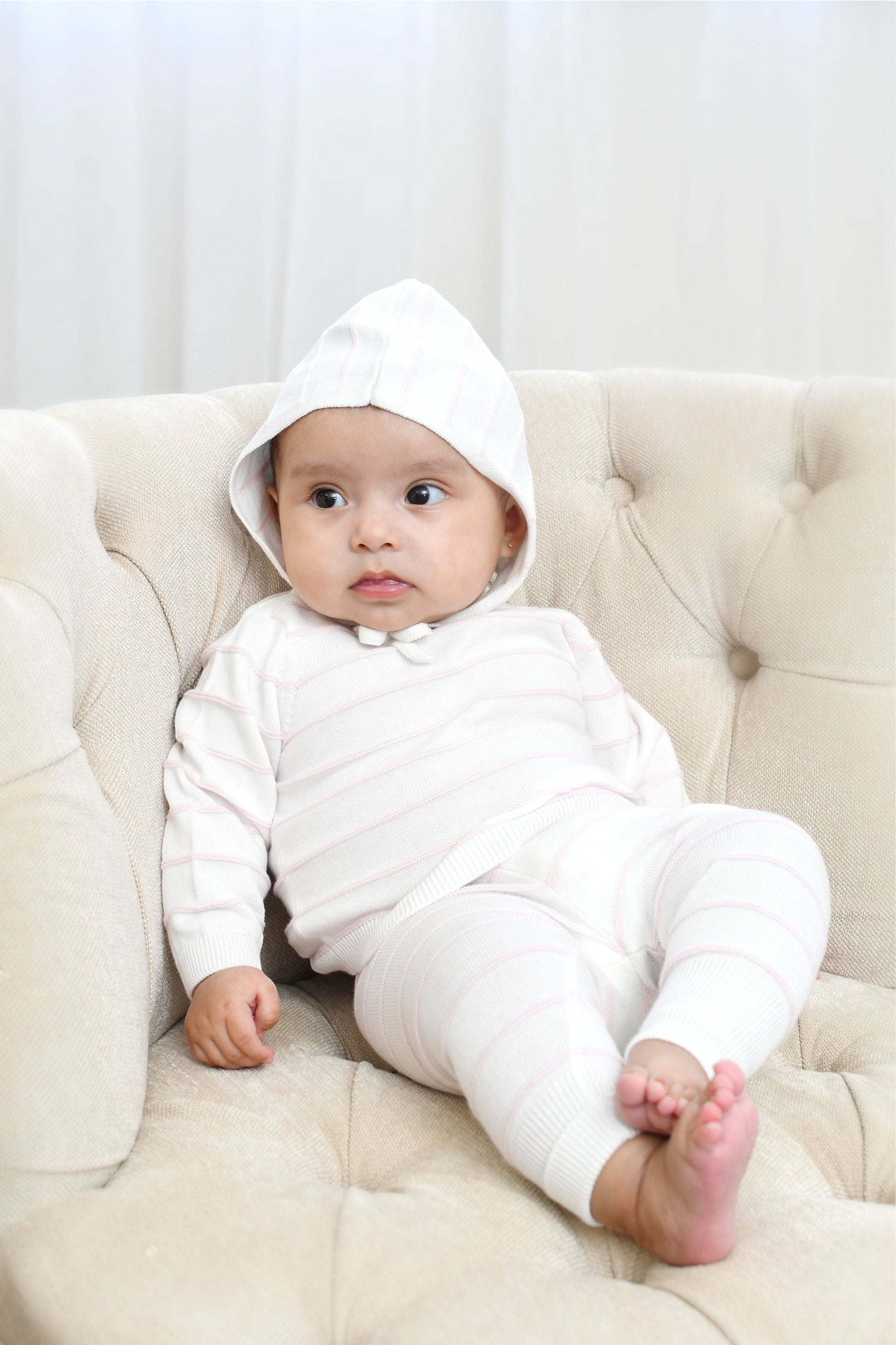 Carriage Boutique baby wearing a creamy white knit set with blush pink stripes, long sleeves, leggings, and a matching hat.
