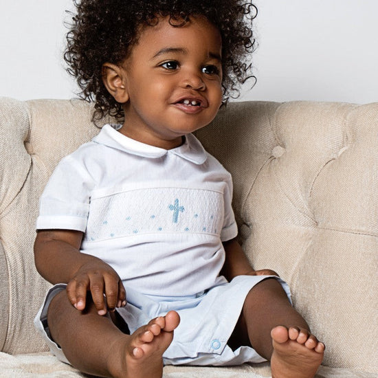 Carriage Boutique baby boy's light blue smocked christening bobbie suit with blue cross embroidery and Peter Pan collar.