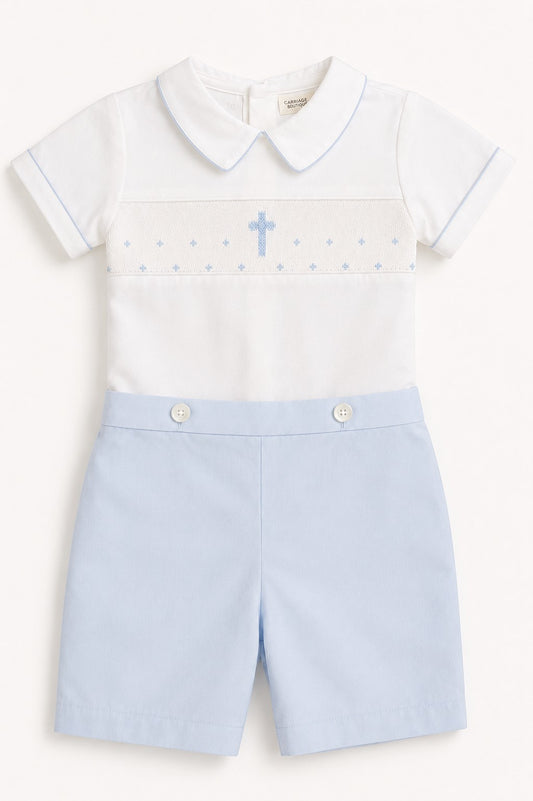 Carriage Boutique white short-sleeve bobbie suit with blue smocking, cross, and light blue shorts.