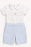 Carriage Boutique white short-sleeve bobbie suit with blue smocking, cross, and light blue shorts. 100% cotton.