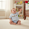 Carriage Boutique light blue cotton baby boy bubble romper with hand-smocked blue dogs in wagons on the chest.