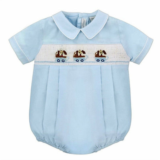 Carriage Boutique light blue cotton baby boy bubble romper with hand-smocked white panel featuring blue dogs in wagons.
