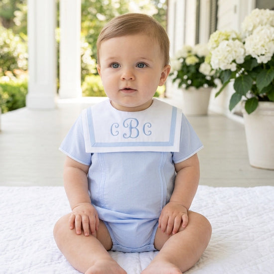Carriage Boutique baby boy bubble romper in light blue and white with a monogrammed Peter Pan collar on a toddler.