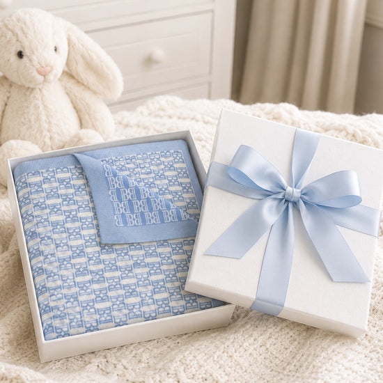 Carriage Boutique blue and white monogram knit baby blanket folded in a gift box with a light blue satin ribbon.