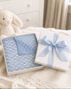 Carriage Boutique blue and white monogram knit baby blanket folded in a gift box with a light blue satin ribbon.