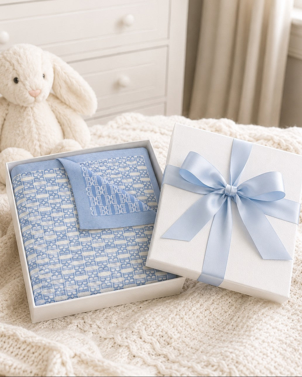 Carriage Boutique blue and white monogram knit baby blanket folded in a gift box with a light blue satin ribbon.