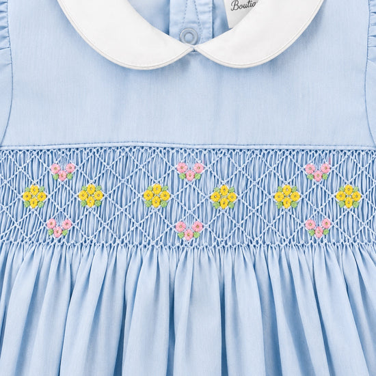 Carriage Boutique blue baby girl dress with white peter pan collar and hand-smocked waist with floral embroidery.