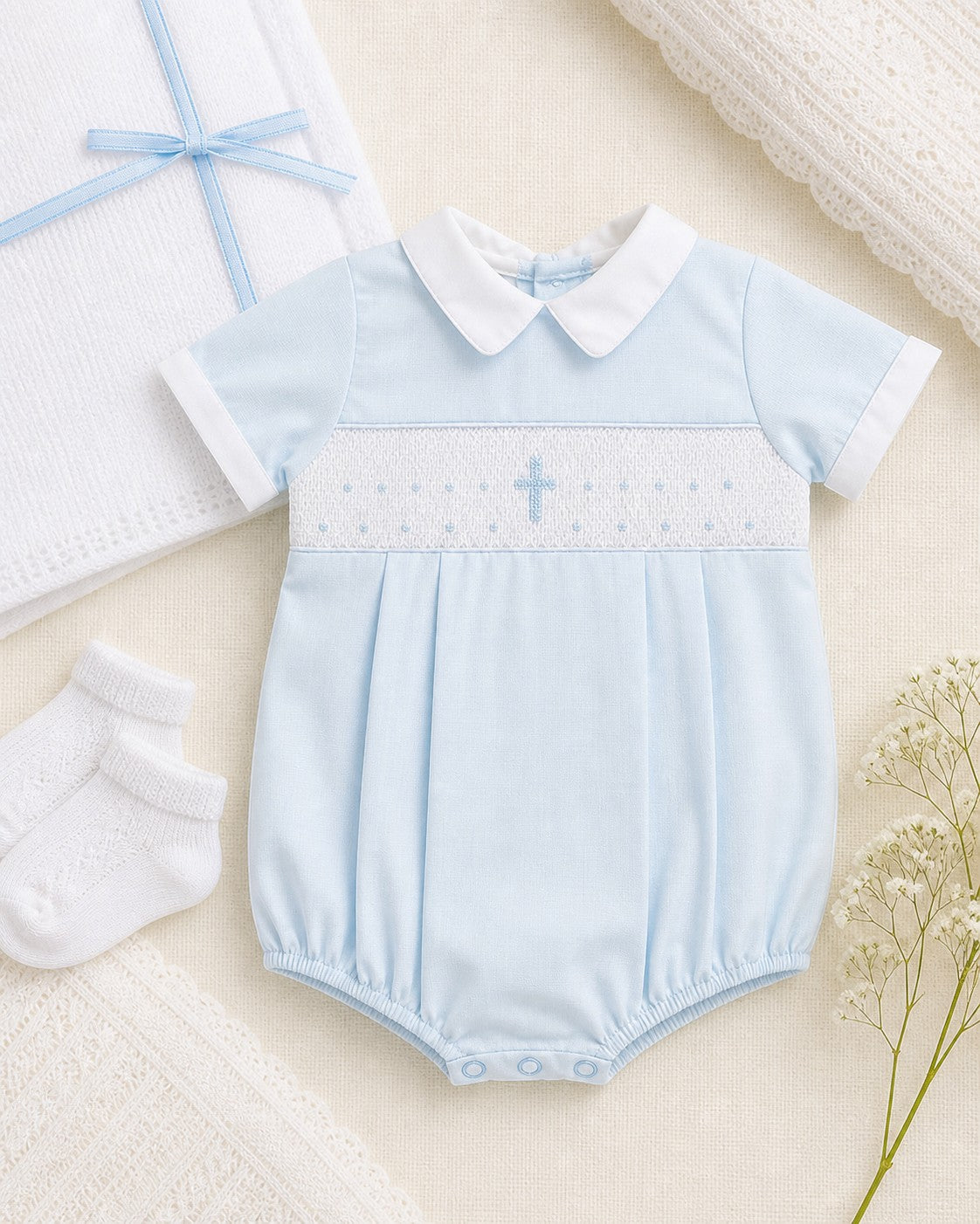 Carriage Boutique blue cotton baby boy bubble romper with white collar and hand-smocked cross detail.