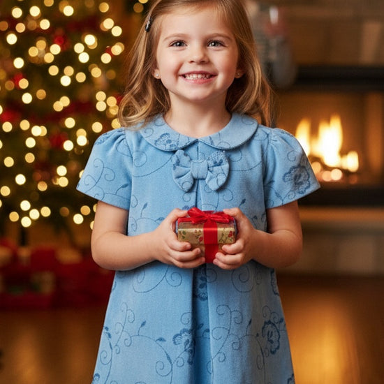 Carriage Boutique toddler girl blue suede party dress with floral pattern and ribbon detail in a festive setting