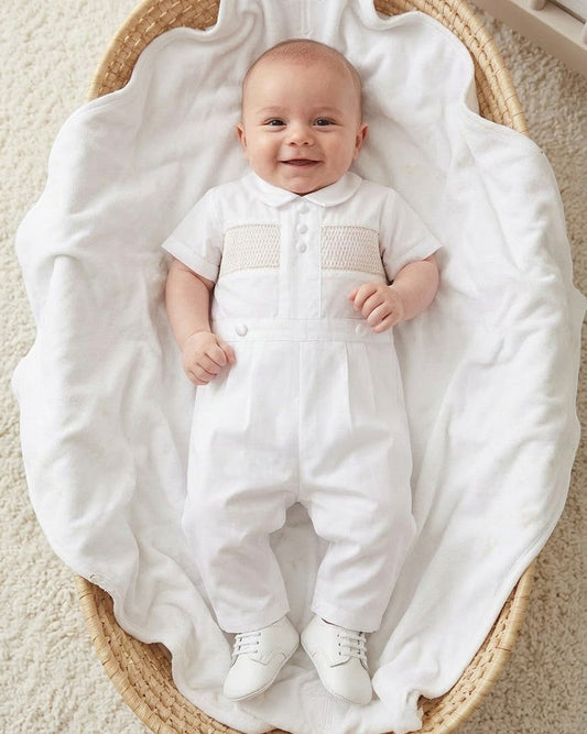 Carriage Boutique white cotton boys christening outfit with hand-smocked detail and satin trim in a wicker basket