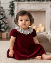 Carriage Boutique burgundy velvet dress for baby girls featuring a delicate white lace collar in a festive setting
