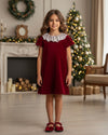 Carriage Boutique burgundy velvet dress with white lace collar worn by a young girl in a festive holiday setting