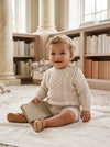 Carriage Boutique baby boy wearing a cream fisherman knit cotton pullover sweater with button shoulder detail