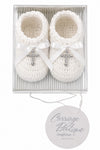 Carriage Boutique white hand-crocheted baby christening shoes with satin bows and gem-adorned cross charms in a box.