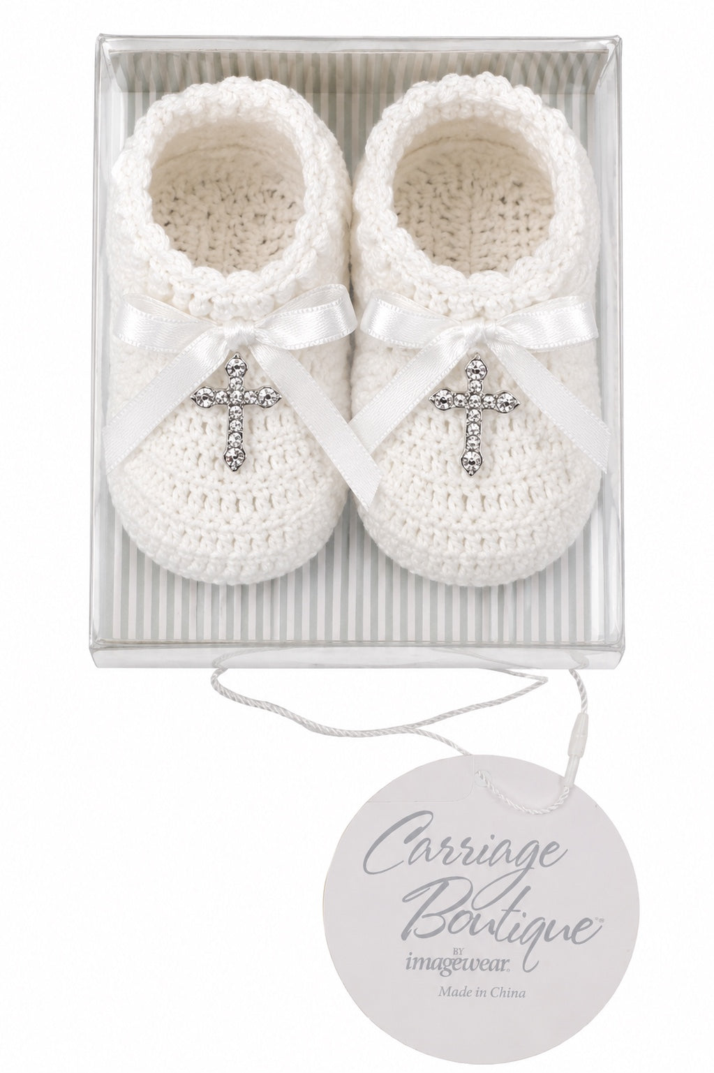 Carriage Boutique white hand-crocheted baby christening shoes with satin bows and gem-adorned cross charms in a box.