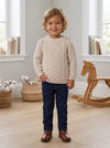 Carriage Boutique beige fisherman knit cotton pullover sweater worn by a smiling toddler boy with jeans and boots