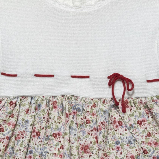 Carriage Boutique baby dress with white knit bodice, lace collar, and floral print skirt with red ribbon detail.