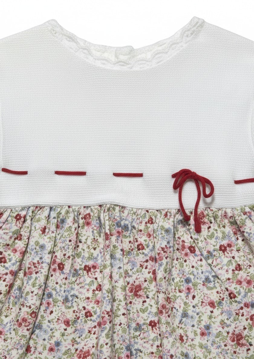 Carriage Boutique baby dress with white knit bodice, lace collar, and floral print skirt with red ribbon detail.