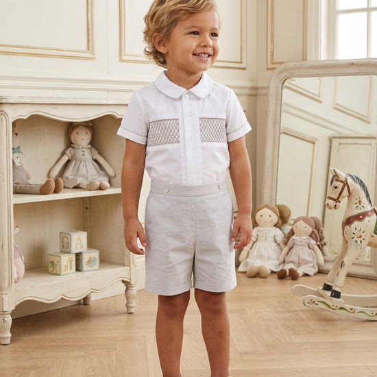 Carriage Boutique gray smocked bobby suit with Peter Pan collar and embroidery on a toddler in a nursery setting.