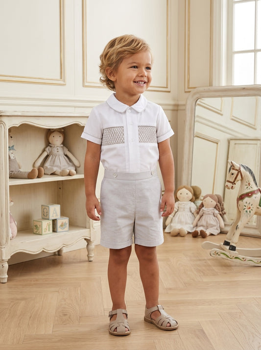 Carriage Boutique gray smocked bobby suit with Peter Pan collar and embroidery on a toddler in a nursery setting.