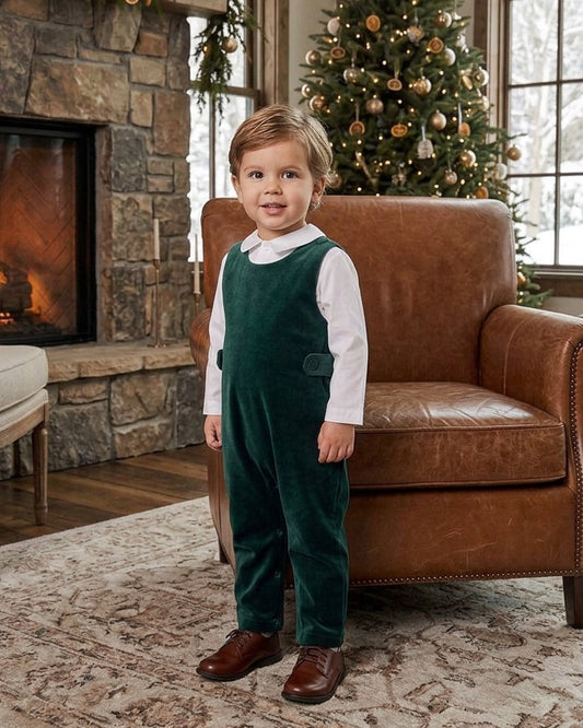 Carriage Boutique baby boy wearing a green velvet long romper over a white collared shirt in a cozy living room.