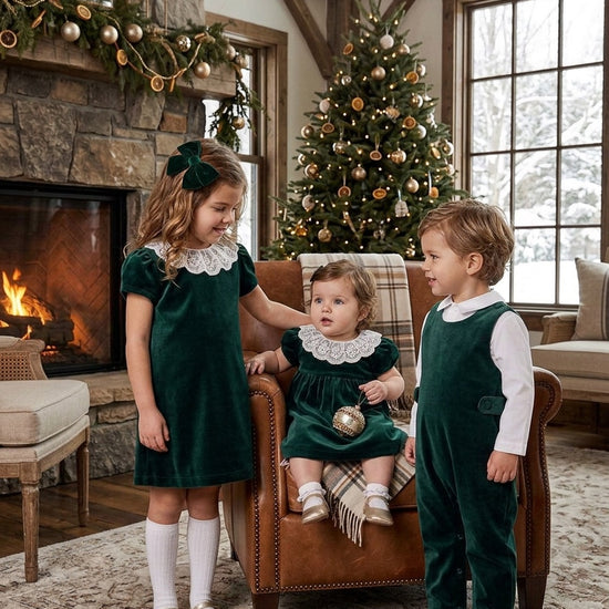Carriage Boutique green velvet toddler dresses with white lace collars worn by two girls in a festive living room