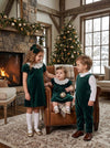 Carriage Boutique green velvet toddler dresses with white lace collars worn by two girls in a festive living room