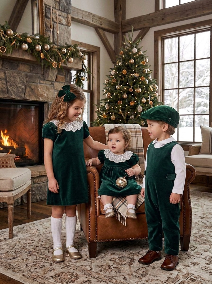 Carriage Boutique green velvet dresses with white lace collars worn by two girls in a festive holiday living room.