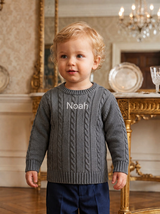 Carriage Boutique grey cable-knit cotton sweater with Noah monogram on chest worn by a toddler boy