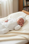 Newborn sleeping in a Carriage Boutique white gown and matching bonnet with a subtle grey star print.