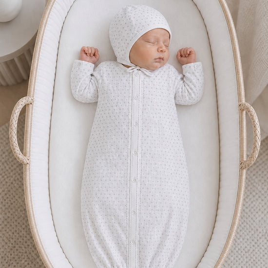 Carriage Boutique infant sleep gown and matching bonnet in white with grey star print, worn by a sleeping newborn.