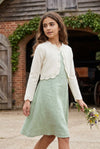 Carriage Boutique ivory cotton bolero shrug sweater with scalloped edges worn by a girl in a green dress