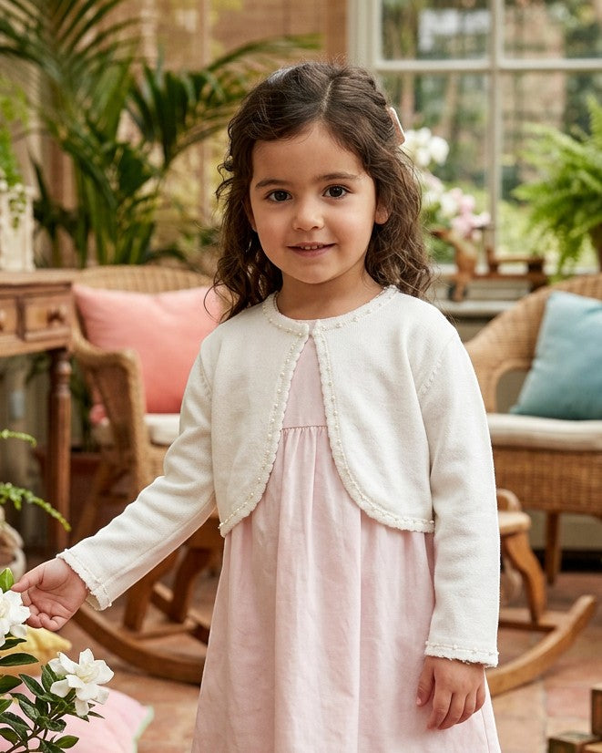 Carriage Boutique ivory knit bolero sweater with pearl trim worn by a toddler girl over a light pink dress