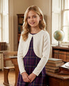 Carriage Boutique ivory knit bolero sweater with pearl trim worn by a young girl over a purple plaid dress